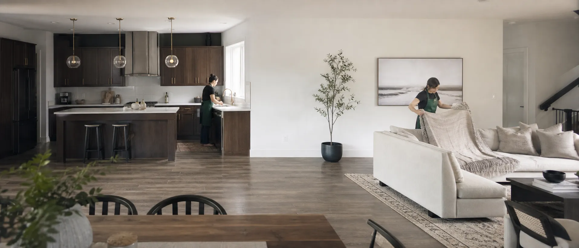 Two cleaners working across an open-plan kitchen and living room